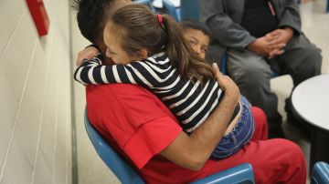 Un inmigrante detenido abraza a sus hijos durante una visita en el centro de Adelanto, en California.