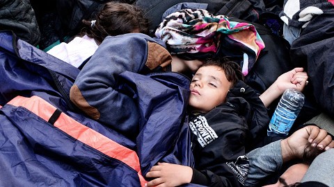 Un niño duerme entre otros refugiados en Victoria Square, Atenas, Grecia.