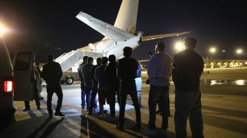 Migrantes que son deportados suben a un avión fletado por ICE para viajar a su país de origen.