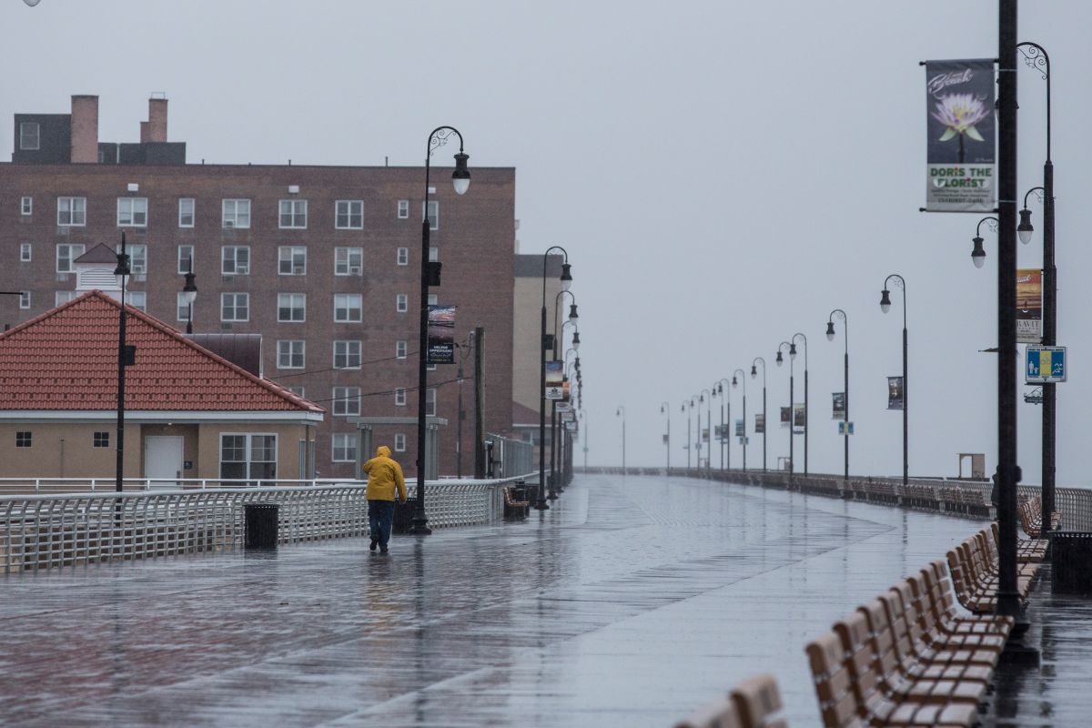 Un hombre camina por el paseo marítimo bajo la lluvia en Long Beach, Nueva York.