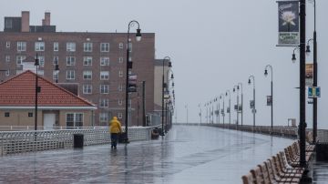 Un hombre camina por el paseo marítimo bajo la lluvia en Long Beach, Nueva York.