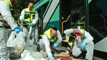 Voluntarios limpian la escena tras un ataque terrorista a un ómnibus en Jerusalén.