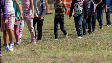 Familias y niños migrantes caminan en línea en el Centro de Detención de la Patrulla Fronteriza en Brownsville, Texas.