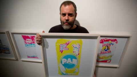 El fotógrafo venezolano Juan Toro posa para un retrato con su imagen de un paquete de harina en una galería de arte en Caracas, Venezuela en una fotografía del 12 de noviembre de 2015. La fotografía forma parte de la exposición "Desaparecidos" sobre productos básicos que enfrentan escasez en Venezuela. Toro trató de preservarlos en la memoria colectiva con su muestra. (Foto AP/Fernando Llano)