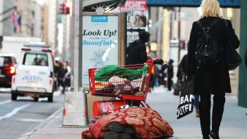 A pasos del Trump Tower este "homeless" duerme en la acera sobre la calle 57 Oeste, mientras la gente camina.
 Mariela Lombard / El Diario.