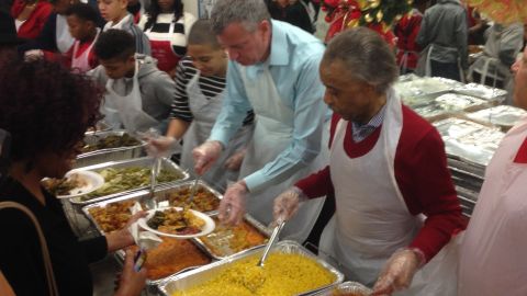 El alcalde Bill de Blasio junto al reverendo Al Sharpton reparten comida a los necesitados.