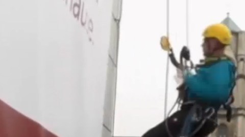 El trabajo de instalar y reemplazar anuncios en rascacielos es de alto riesgo.