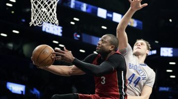 El jugador de Miami Heat Dwyane Wade intenta anotar ante Bojan Bogdanovic de los Nets.