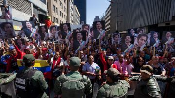 Un grupo de seguidores del fallecido presidente Hugo Chávez gritan consignas y muestran afiches a la afueras de la Asamblea Nacional en Caracas.