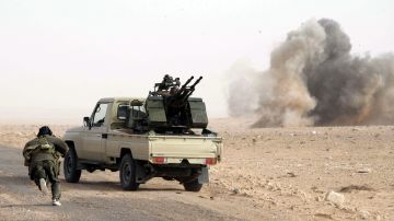 Un rebelde libio corre para protegerse detrás de una camioneta con armas antiaéreas.