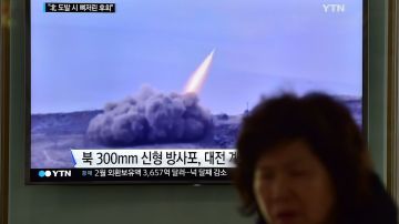Una mujer pasa junto a un televisor que muestra imágenes de archivo de un misil de Corea del Norte, en Seúl, Corea del Sur.