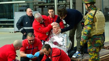 Víctima recibe primeros auxilios de rescatistas cerca de la estación del metro de Maalbeek en Bruselas, tras el atentado a esta estación cercana a los edificios de la Unión Europea que causó varias muertes y centenares de heridos.