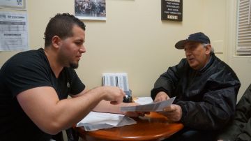 Amaury Abreu, quien trabaja en el food pantry de Reaching-Out Community Services en Brooklyn, asesora a un jubilado a hacer su declaración de impuestos./Gerardo Romo