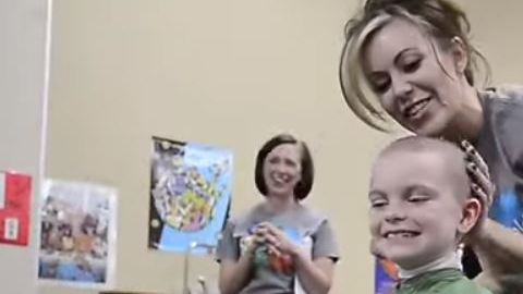 Marlee Pack, la niña diagnosticada con cáncer, sostiene el pelo de una de sus compañeras.