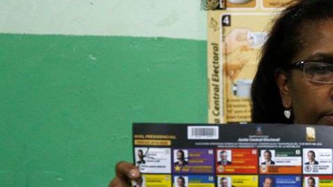 Una vocal de una mesa de votación sostiene un voto durante el conteo tras el cierre de los colegios en Santo Domingo.