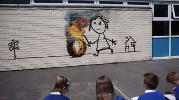 El nuevo mural de Banksy representa a un niño jugando con una rueda en llamas.