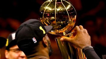 LeBron James se mira en el reflejo del preciado trofeo Larry O'Brien. El retrato de un campeón y el premio a una misión cumplida.