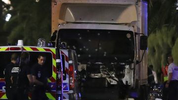 Policías cerca de una furgoneta, con su parabrisas acribillado, que chocó contra una multitud durante un espectáculo de fuegos artificiales en la ciudad de Niza, en Francia.