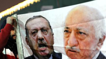 Un manifestante sostiene una pancarta con imágenes del primer ministro turco, Recep Tayyip Erdogan (c) y el clérigo turco con sede en EEUU Gülen (i) durante una manifestación contra el gobierno el 30 de diciembre de 2013 en Estambul.