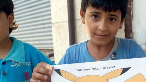 Niños sirios sostienen carteles con fotos de Pokémon y un mensaje "Soy de Siria, sálvame".