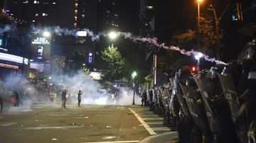 Varios manifestantes se encaran a policías antidisturbios durante las protestas ocurridas anoche por segundo día consecutivo en Charlotte.