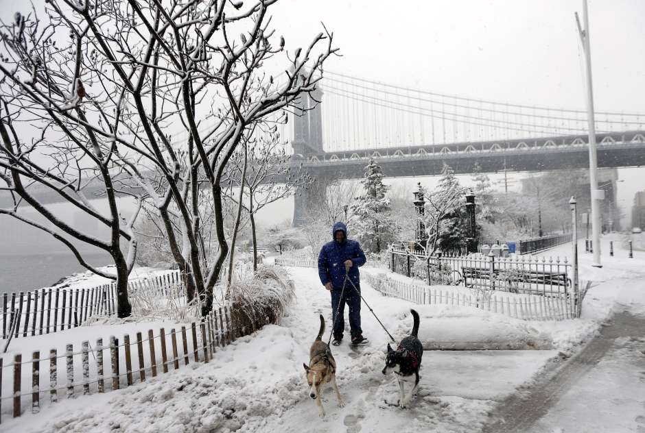 MHR05 NUEVA YORK (ESTADOS UNIDOS), 05/03/2015.- Un hombre pasea a sus perros en los alrededores del puente de Brooklyn cubiertos de nieve en la orilla de Brooklyn del East River en Nueva York, Estados Unidos, hoy, jueves 5 de marzo de 2015. Se espera que en el área de la ciudad de Nueva York la nieve alcance un espesor de entre 10 y 20 centímetros. EFE/Andrew Gombert