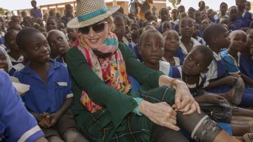 Madonna sentada junto a niños malawíes durante su visita a la primaria Mkoko, una de las escuela construidas por Raising Malawi, la fundación de la cantante.