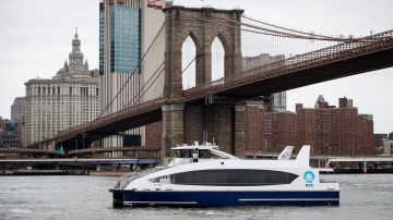 Un ferry cruza el "Brooklyn Bridge" en el East River, NYC.