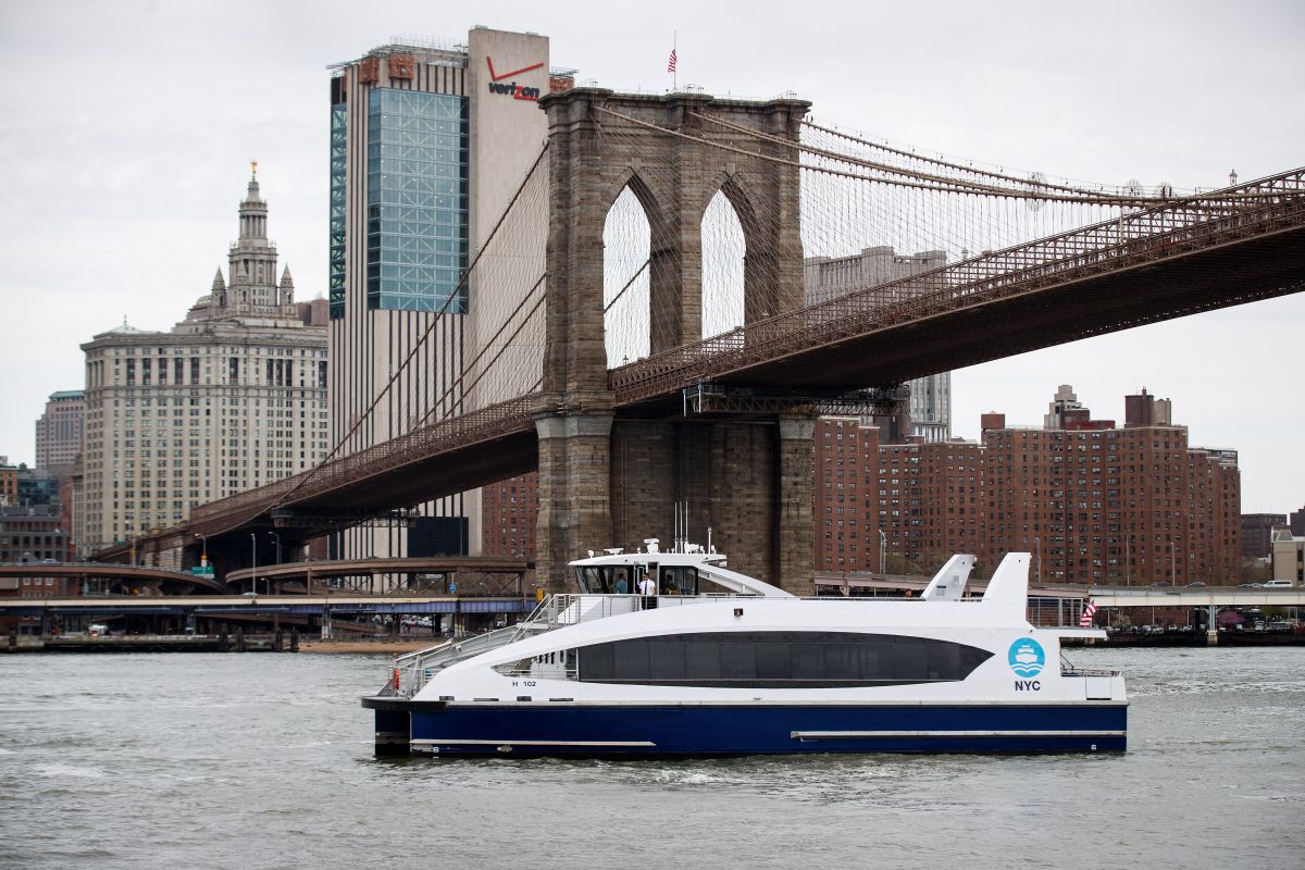 Un ferry cruza el "Brooklyn Bridge" en el East River, NYC.