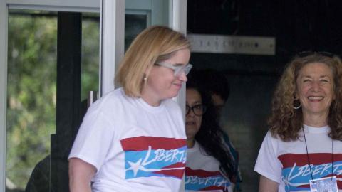 Escoltado por la alcaldesa sanjuanera, López realiza una señal de que todo estará bien.