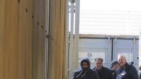 Inmigrantes nigerianos esperan el pasado martes a que varios autobuses los trasladen desde el "punti di crisi" de Pozzallo, vigilado por agentes italianos y europeos de la agencia Frontex.