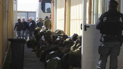 Inmigrantes nigerianos esperan el pasado martes a que varios autobuses los trasladen desde el "punti di crisi" de Pozzallo, vigilado por agentes italianos y europeos de la agencia Frontex.