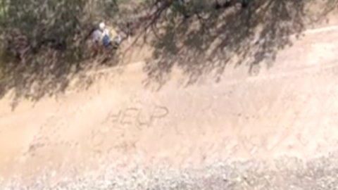 Mensaje de ayuda escrito por una pareja perdida en una isla.