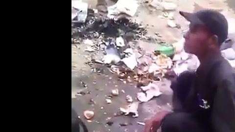 El hombre, rodeado de otros, descuartiza al perro.