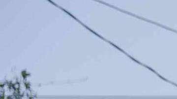 Un hombre protesta encima de un vehículo quemado.