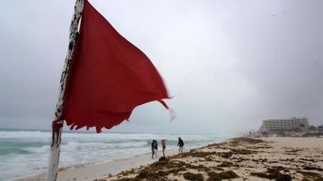 Turistas recorren la zona de playas en Cancún, que muestra la alerta de precaución debido al paso de la tormenta Alberto.