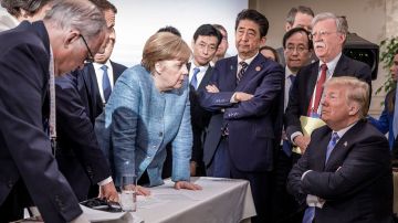 JD100. Charlevoix (Canada), 09/06/2018.- A handout photo made available by the German Government (Bundesregierung) on 09 June 2018 shows French President Emmanuel Macron (3-L, partially hidden), German Chancellor Angela Merkel (C-L) and Japan's Prime Minister Shinzo Abe (C-R) speaking to US Presidend Donald J. Trump (R, seated) during the second day of the G7 meeting in Charlevoix, Canada, 09 June 2018. Looking on is US National Security Advisor John R. Bolton (R, standing); others are not identified. (Japón) EFE/EPA/JESCO DENZE HANDOUT HANDOUT EDITORIAL USE ONLY/NO SALES