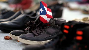 View of a Puerto Rican flag placed on a pair of shoes among hundreds displayed in memory of those killed by Hurricane Maria in front of the Puerto Rican Capitol, in San Juan on June 1, 2018. - Hurricane Maria, which pummeled Puerto Rico in September 2017, is likely responsible for the deaths of more than 4,600 people, some 70 times more than official estimates, US researchers said Tuesday. (Photo by Ricardo ARDUENGO / AFP)        (Photo credit should read RICARDO ARDUENGO/AFP/Getty Images)