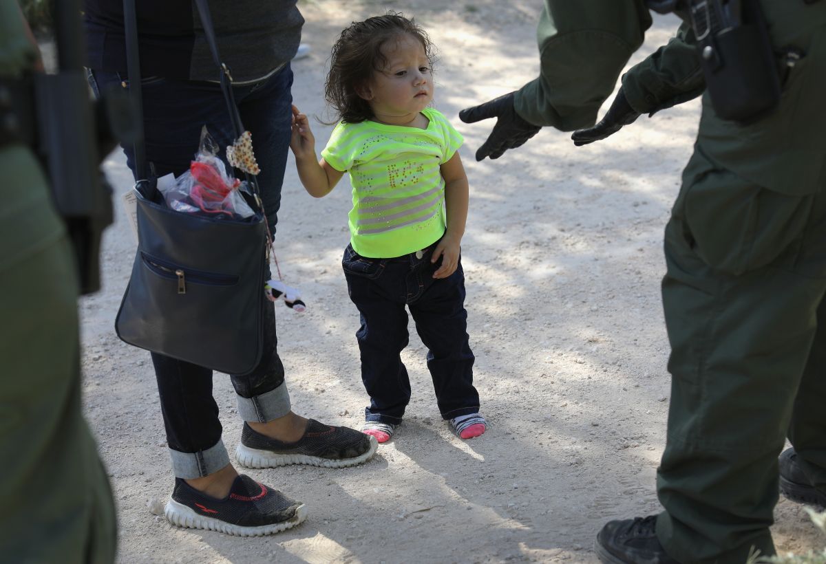 Agente de CBP toma en custodia a una niña y a su madre solicitantes de asilo.