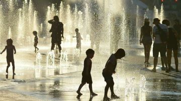 Niños juegan con agua para combatir el calor en Montreal.