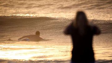 Un hombre surfea las olas en el Océano Atlántico en la playa Wrightsville en Carolina del Norte, estado que espera el azote de Florence.