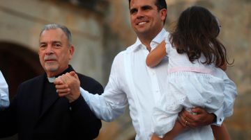 Monseñor Wilfredo Peña y Rosselló con su hija en brazos durante el acto