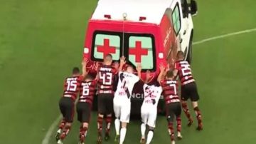 Jugadores del Flamengo y el Vasco da Gama empujan una ambulancia en la cancha.