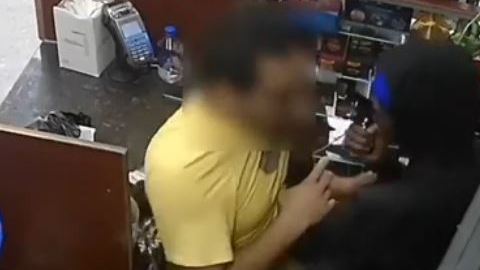 Momento en que se ve al delincuente apuntar al empleado en la cabeza con el arma.