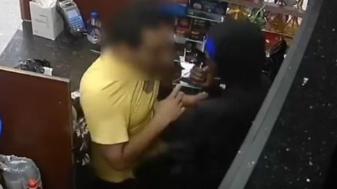 Momento en que se ve al delincuente apuntar al empleado en la cabeza con el arma.