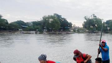 Un grupo de migrantes hondureños cruza ilegalmente el río Suchiate en balsas para llegar a México desde Tecún Umán.
