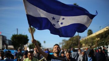 Miembros de una de las caravanas migrantes. En primer plano,  portan la bandera de Honduras.