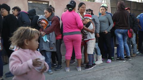 Migrantes esperan por comida en un albergue en Tijuana.