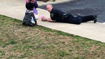 Un policía juega con una niñas para que le pierdan el miedo.