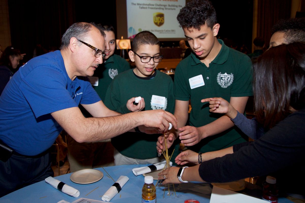 Jairo Torres, quien se desempeña como Laboratory Asset Care Manager en Bristol-Myers Squibb, brinda asesoría a los estudiantes durante el Marshmallow Challenge de la conferencia juvenil de HISPA. 